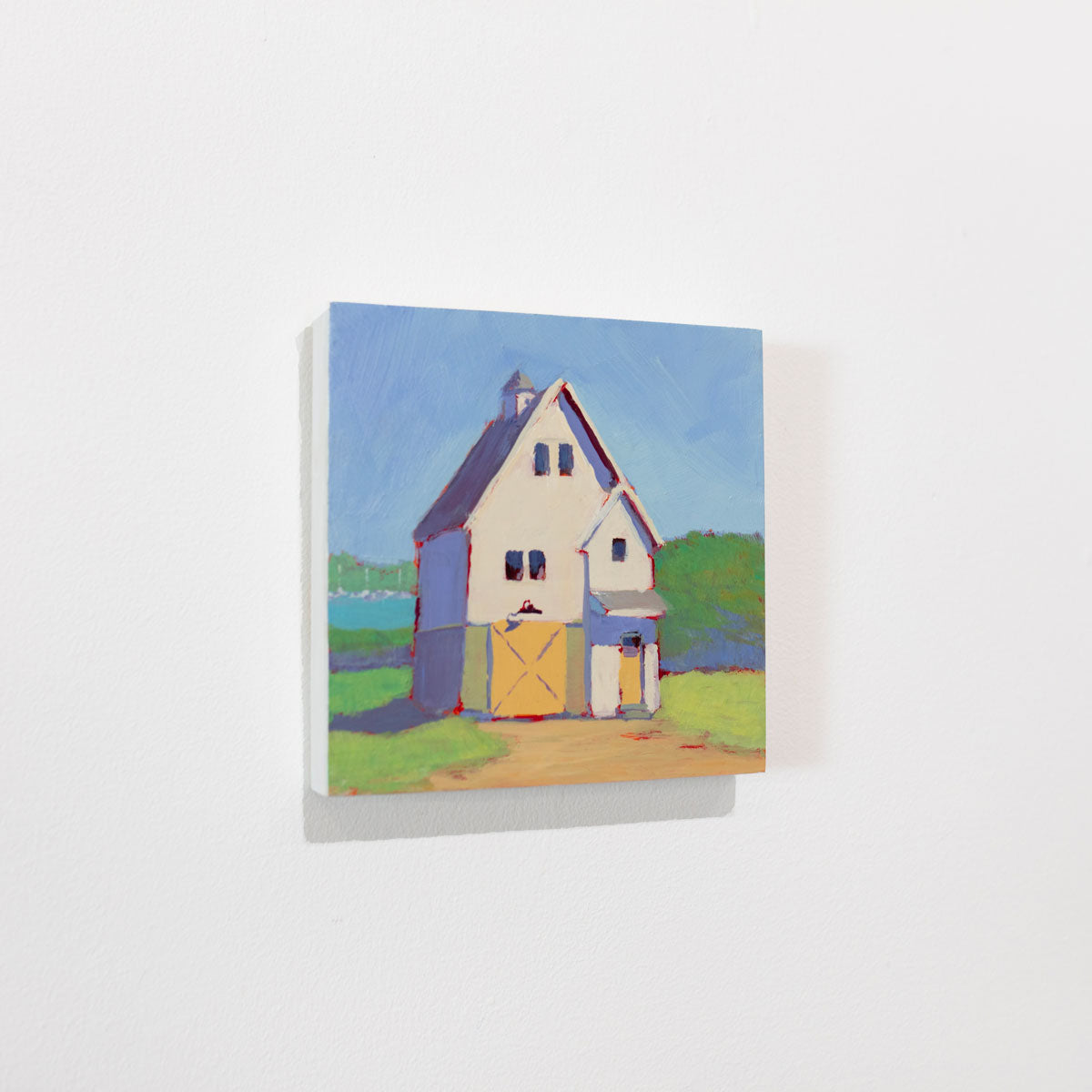 A green, blue, violet, and yellow painting of a house hangs on a white wall.