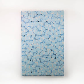 An abstract blue and white painting hangs on a white wall. 