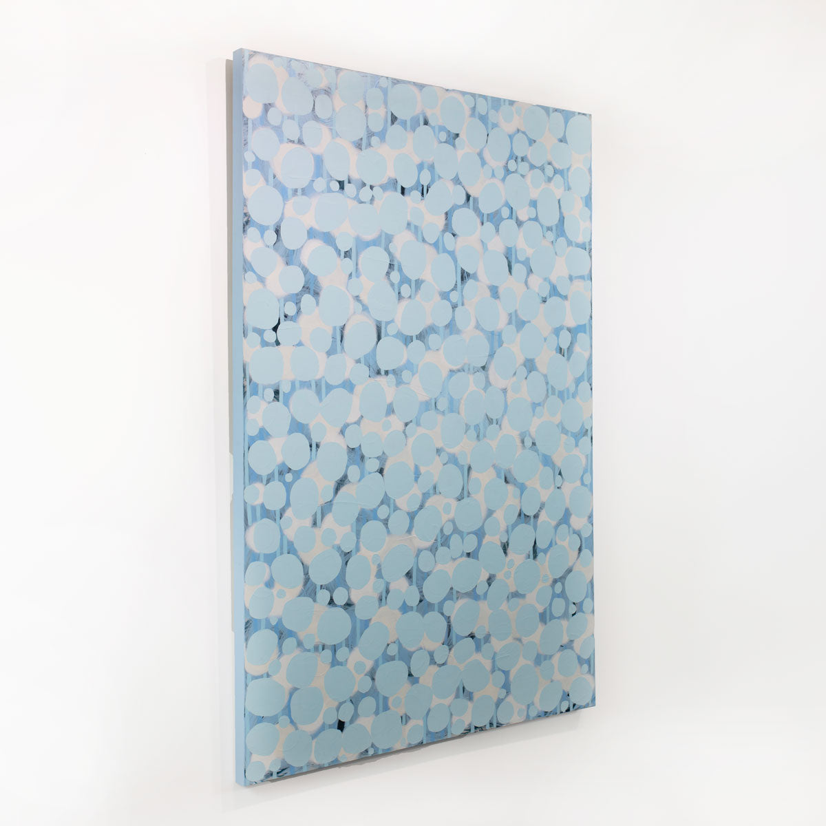An abstract blue and white painting hangs on a white wall.