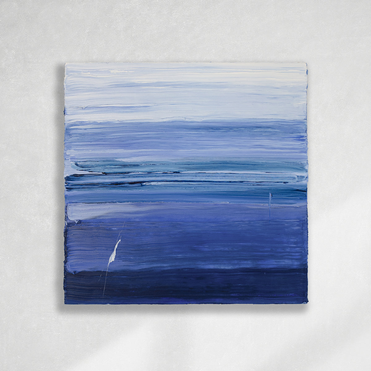 A blue and white textured abstract painting by Teodora Guererra hangs on a white wall.