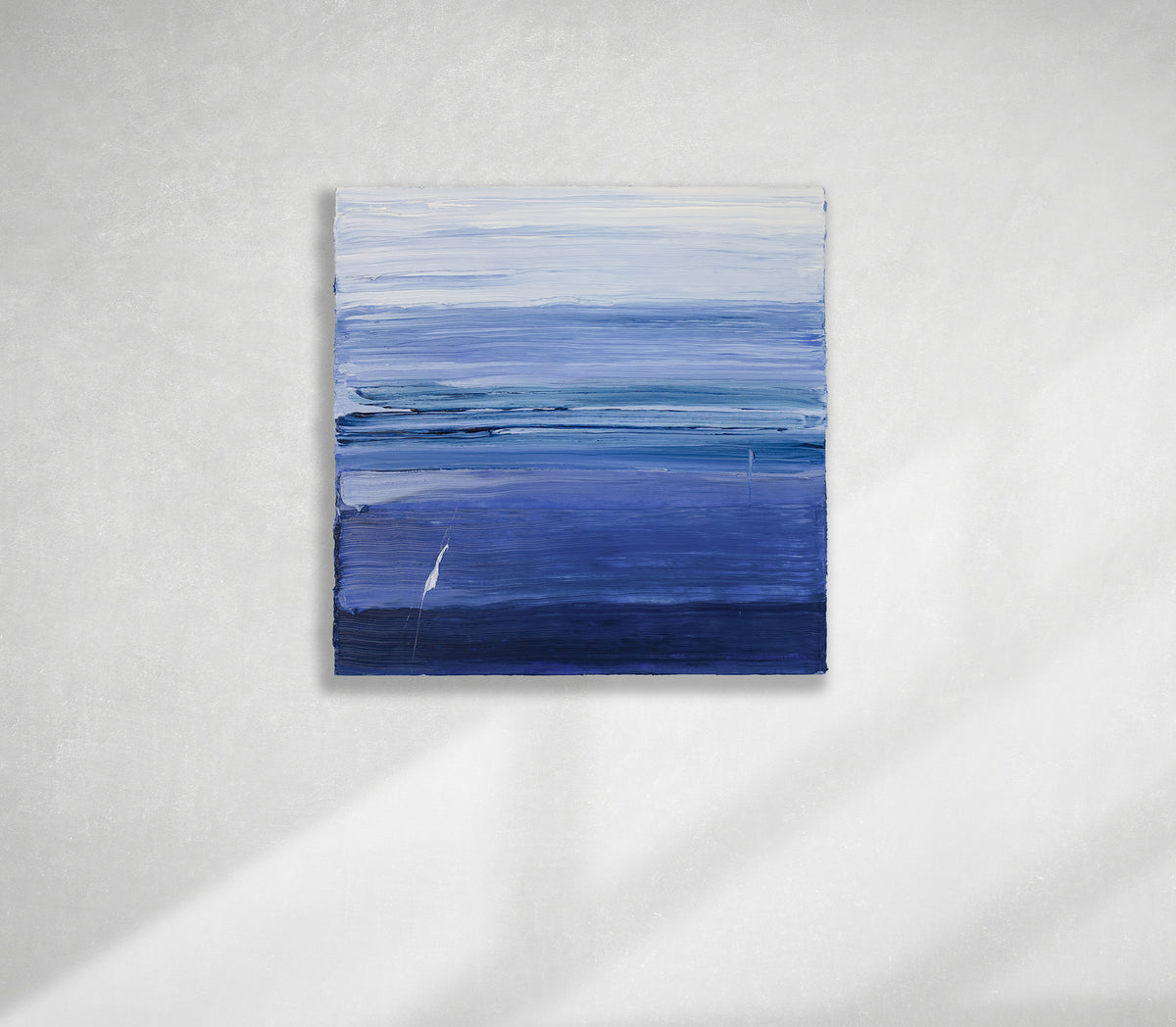 A blue and white textured abstract painting by Teodora Guererra hangs on a white wall.