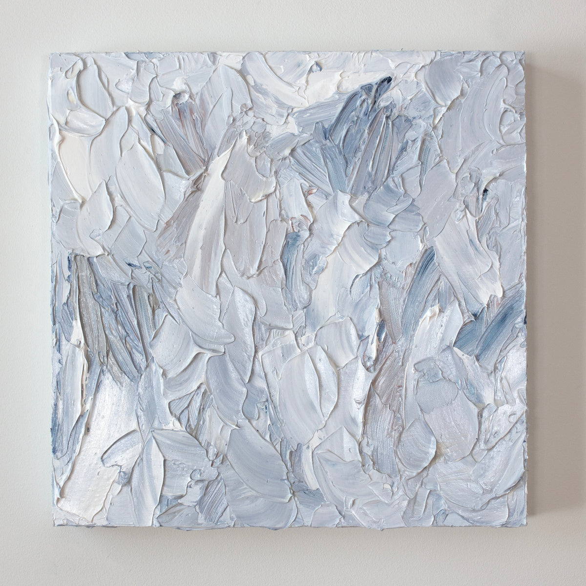 A painting is hanging on a wall. Its surface is decorated with white, blue and grey paint in a thick impasto. Wired and ready to hang.