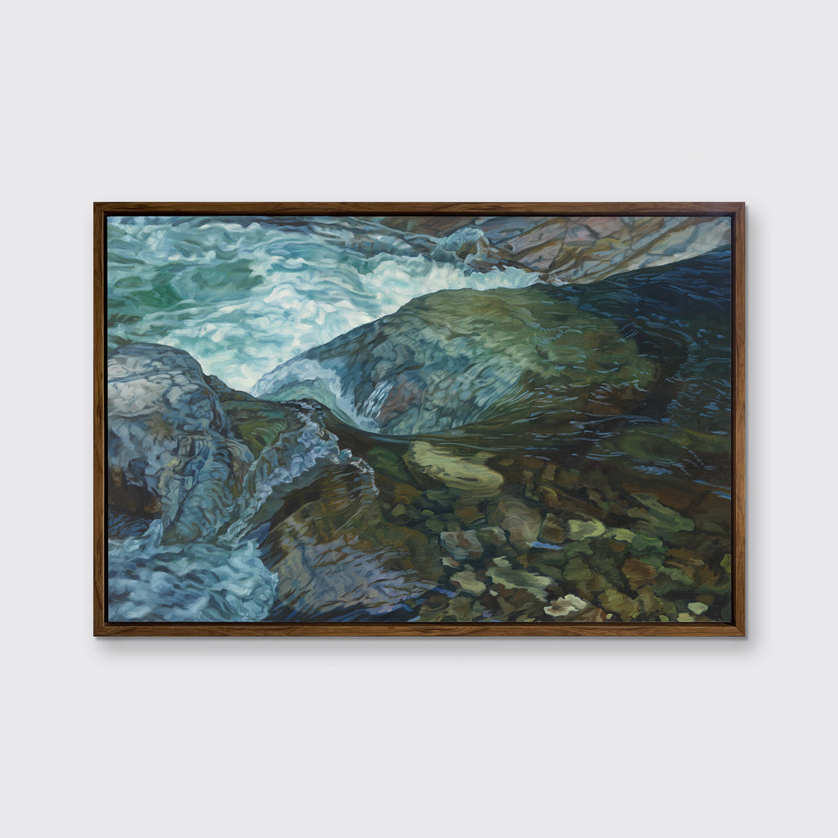 A print of a river bed scene framed in a wood frame hangs on a white wall.
