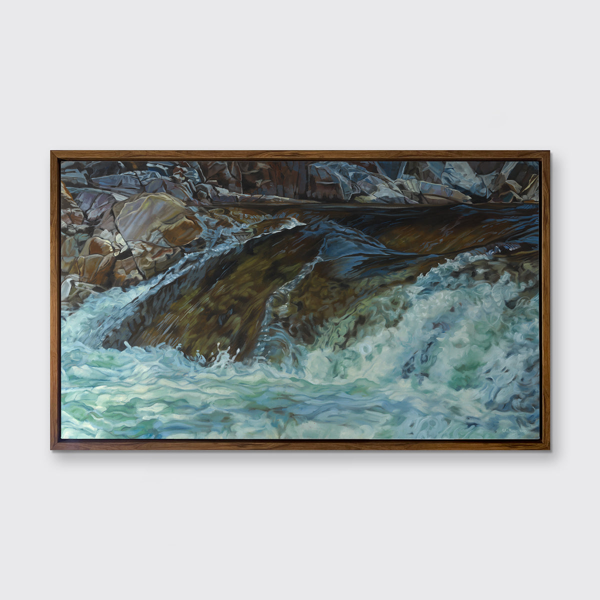 A print of river water streaming over rocks framed in a wood frame hangs on a white wall. 