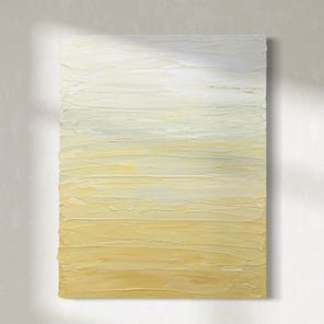 A Yellow, seafoam green and white textured painting by Teo Guererra hangs on a wall in the sunlight.