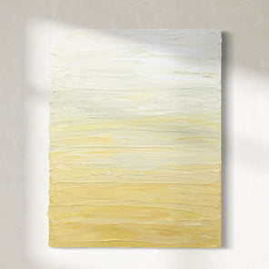 A Yellow, seafoam green and white textured painting by Teo Guererra hangs on a wall in the sunlight.