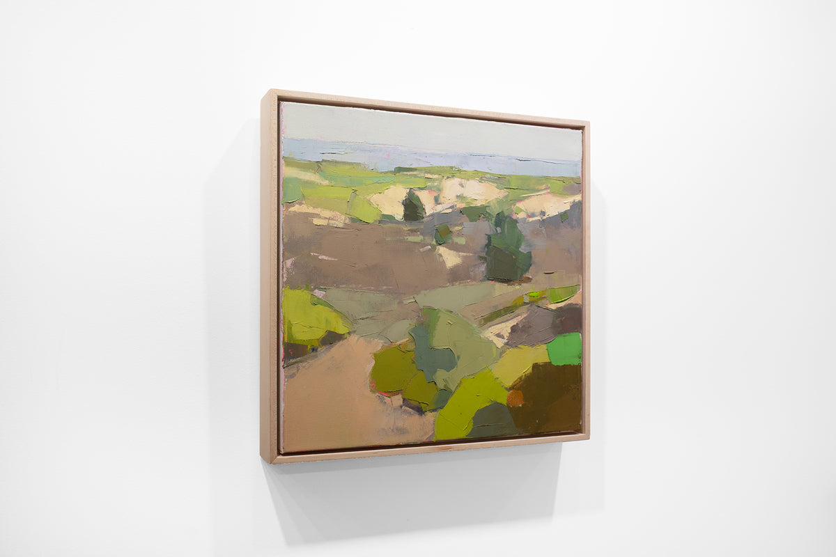 A small framed green and brown landscape painting hangs on a white wall.
