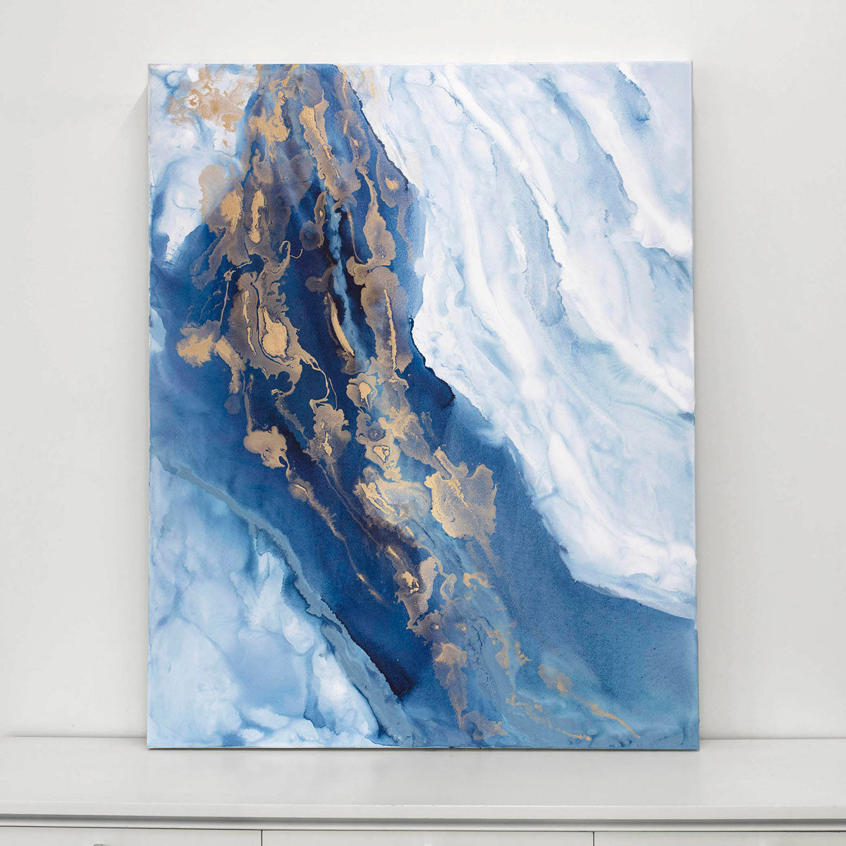 Abstract art painting with blue and gold tones on a white wall