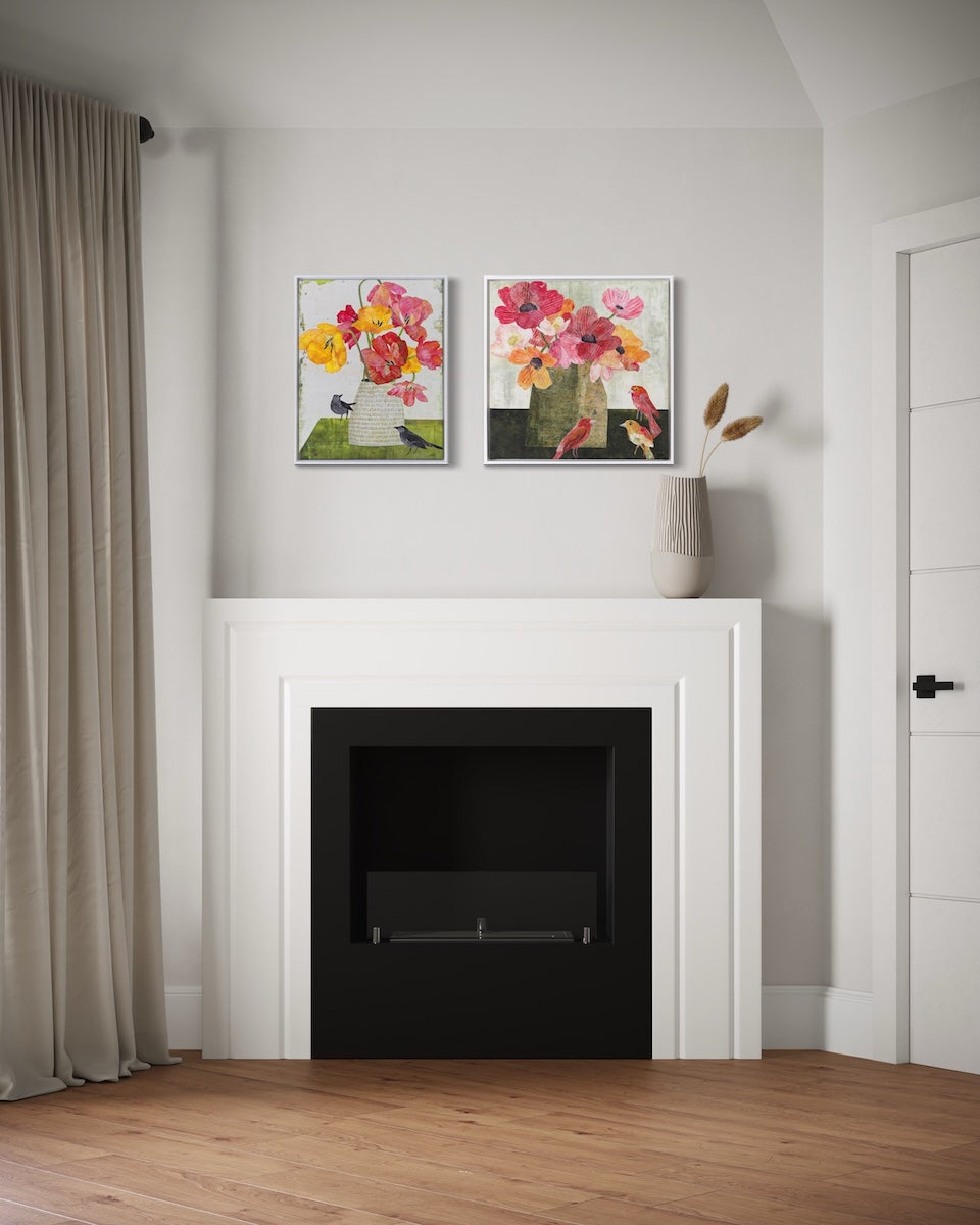 A modern interior scene featuring a white fireplace with a black insert, flanked by a beige curtain and a white door. Above the fireplace are two framed colorful floral collage paintings, and a small beige vase with dried stems sits on the mantel.