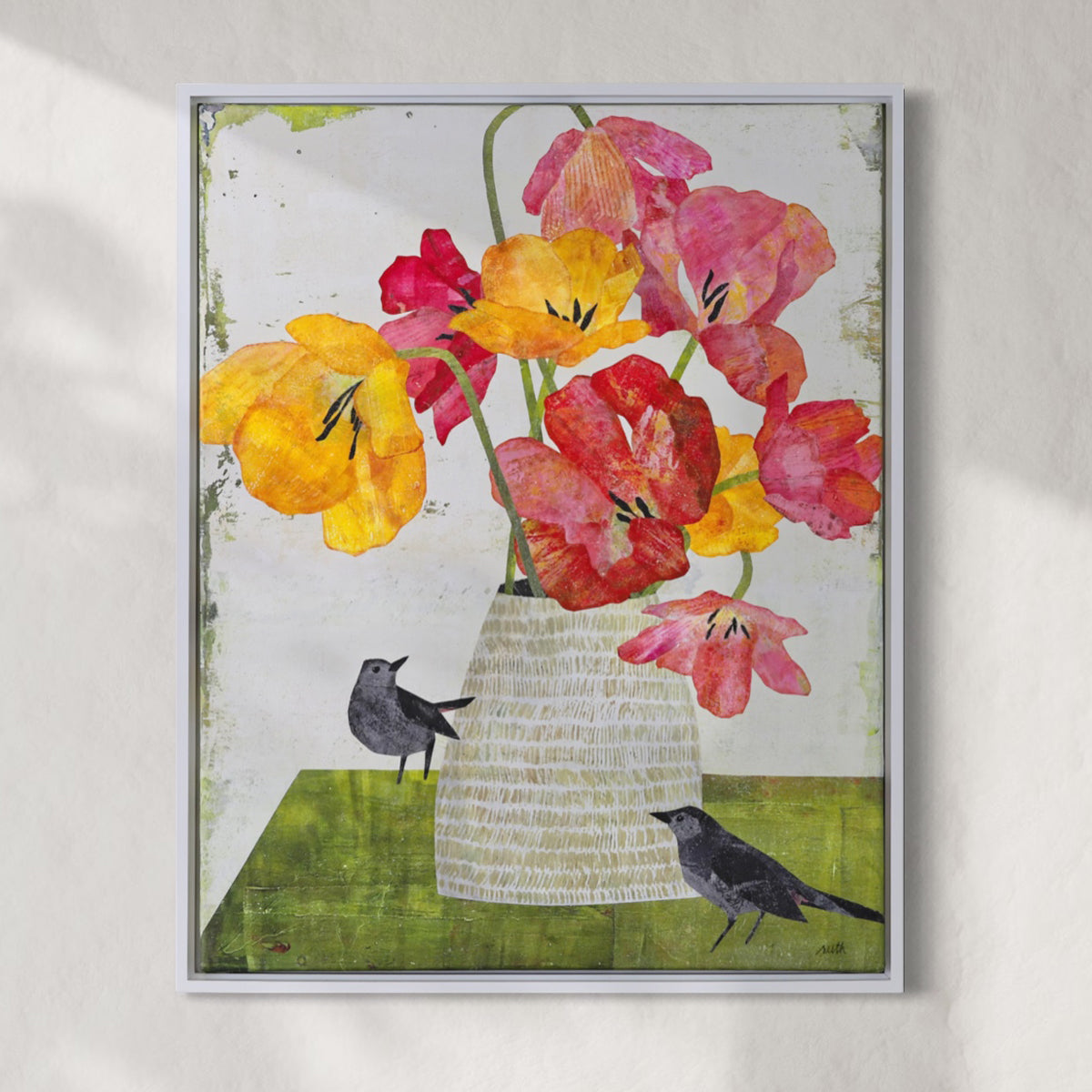 Framed collage featuring a colorful still life of flowers in a vase with two small birds, displayed against a light textured wall.