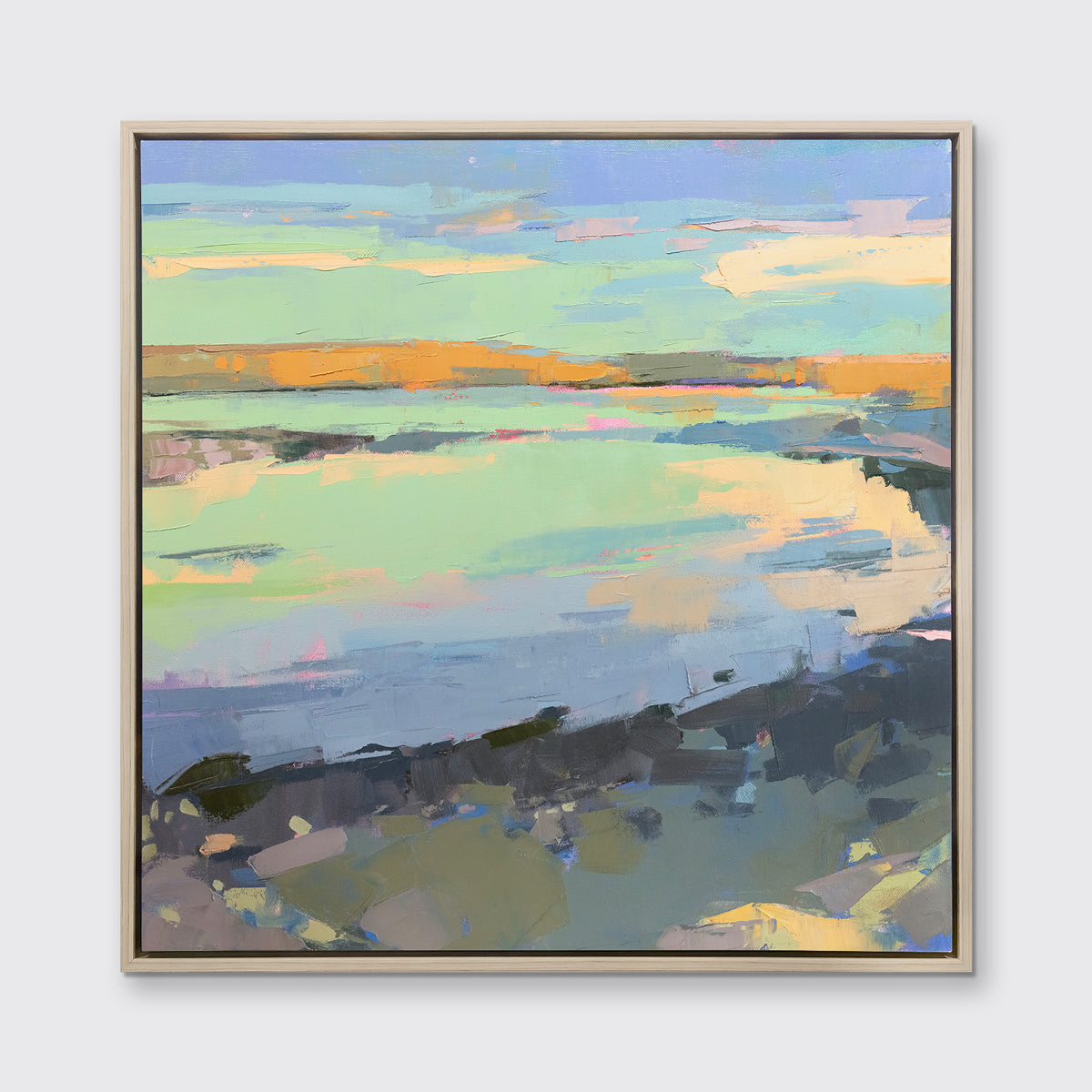 A colorful abstract landscape print framed in a white oak frame hangs on a white wall.