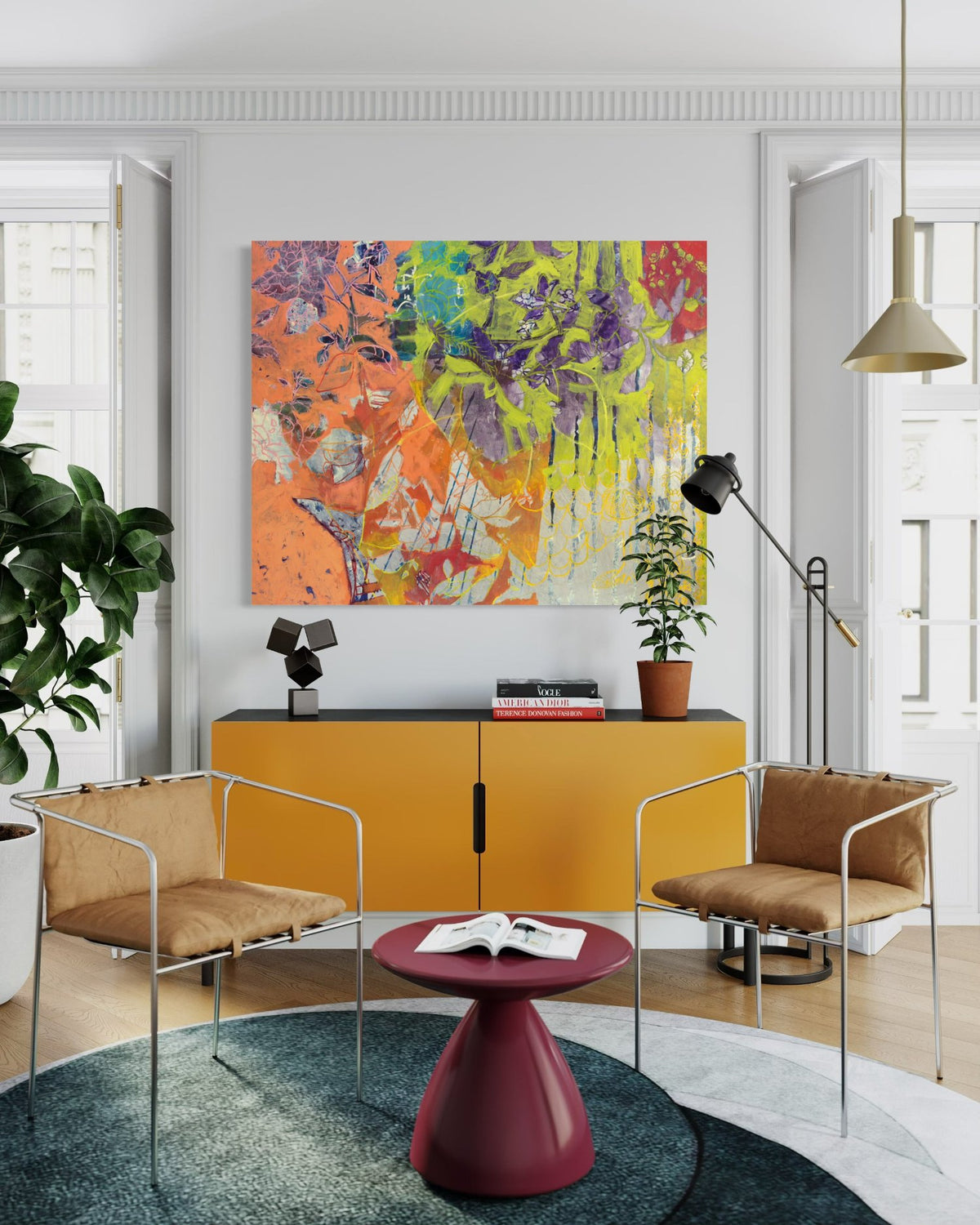 A painting with beautiful floral motifs in neon green, purple, orange, and blue is hung in a living room over an orange credenza. The painting is wired and ready to hang.