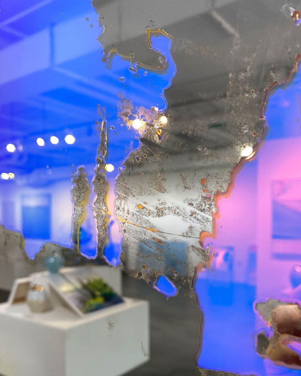 A detail image of a fine art mirror reflecting the art gallery in which it hangs.