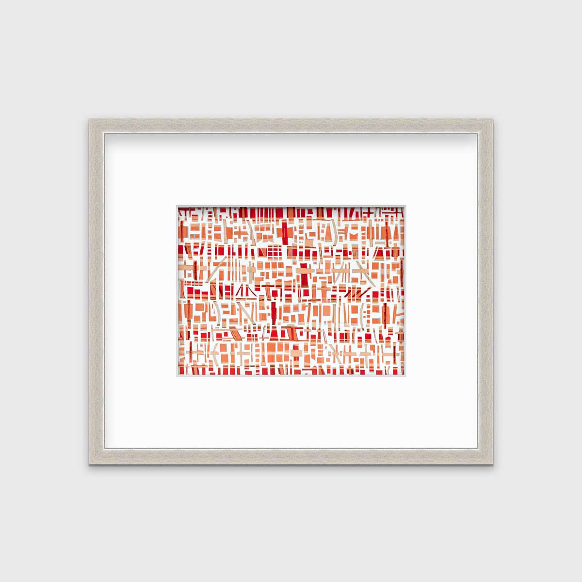 A red, white and orange abstract print in a silver frame with a mat hangs on a white wall.