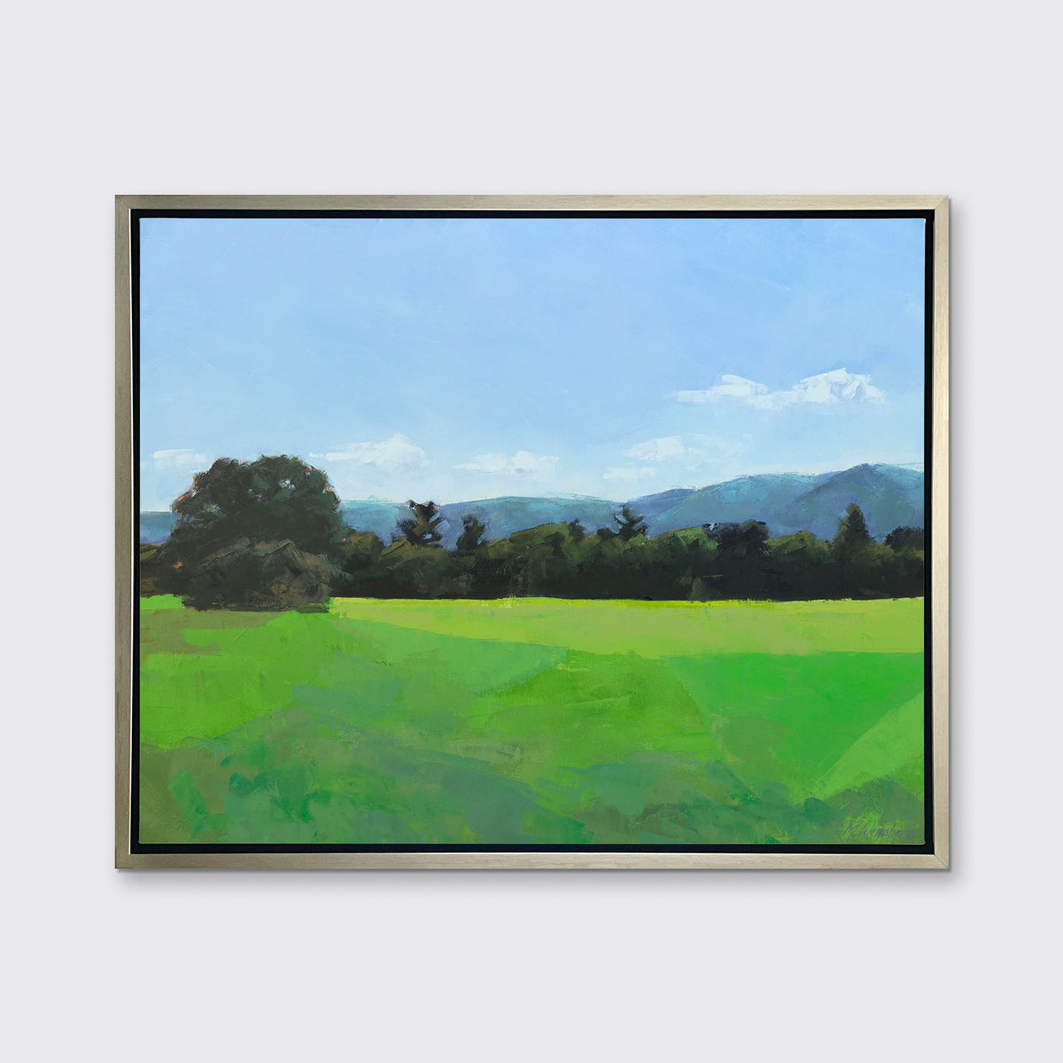 A landscape print in a silver floater frame hangs on a white wall.