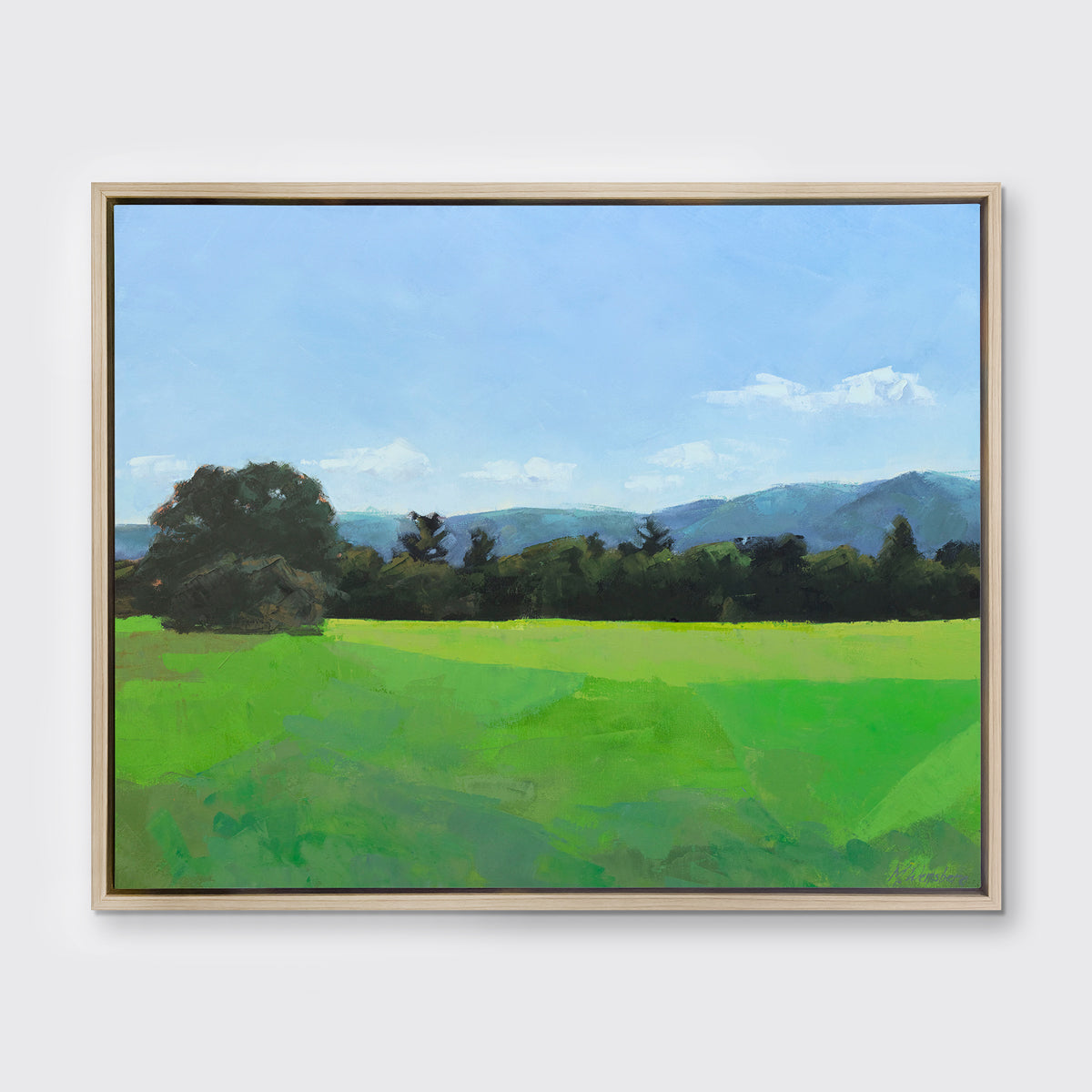 A landscape print in a white oak wood floater frame hangs on a white wall.