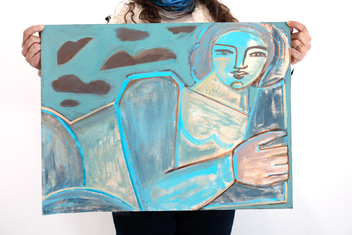 A woman holds a blue, brown, and yellow painting of an abstracted woman in front of a white wall. 