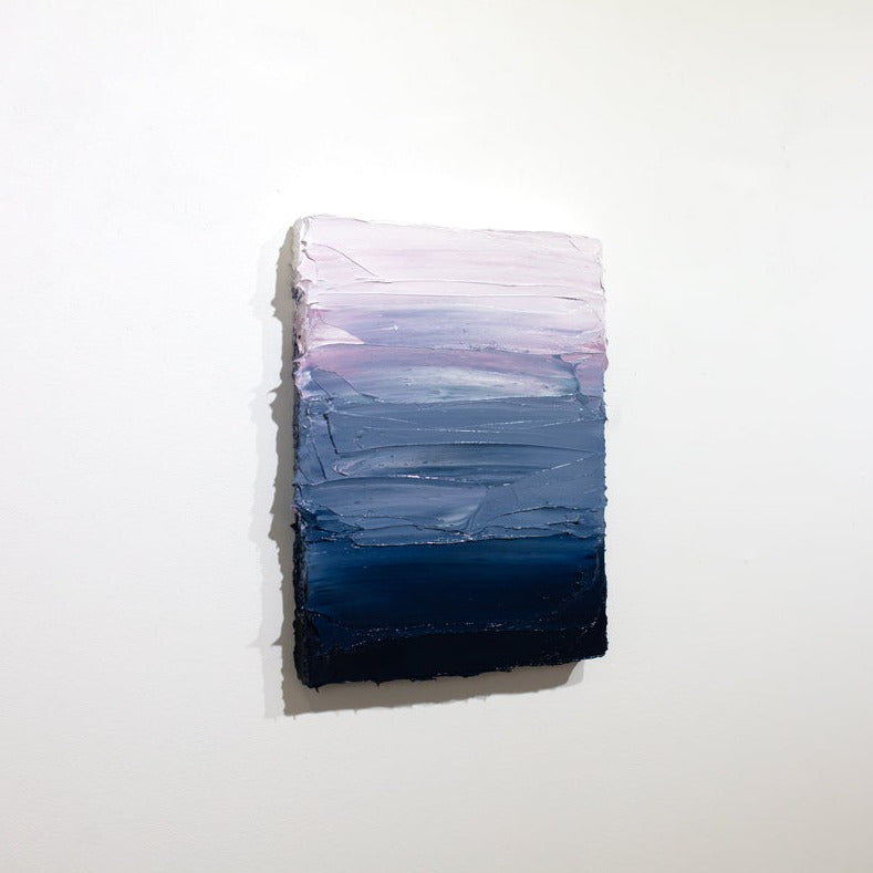 A side view of a blue, lavender and white textured painting on a white wall.