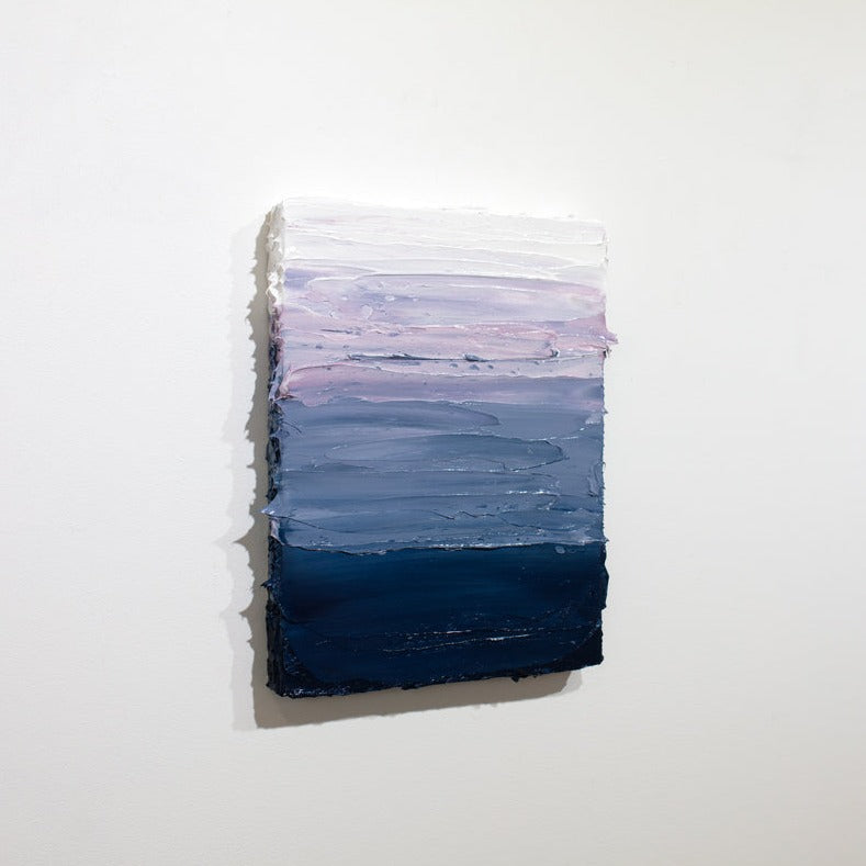 A side view of a blue, lavender and white textured painting on a white wall.