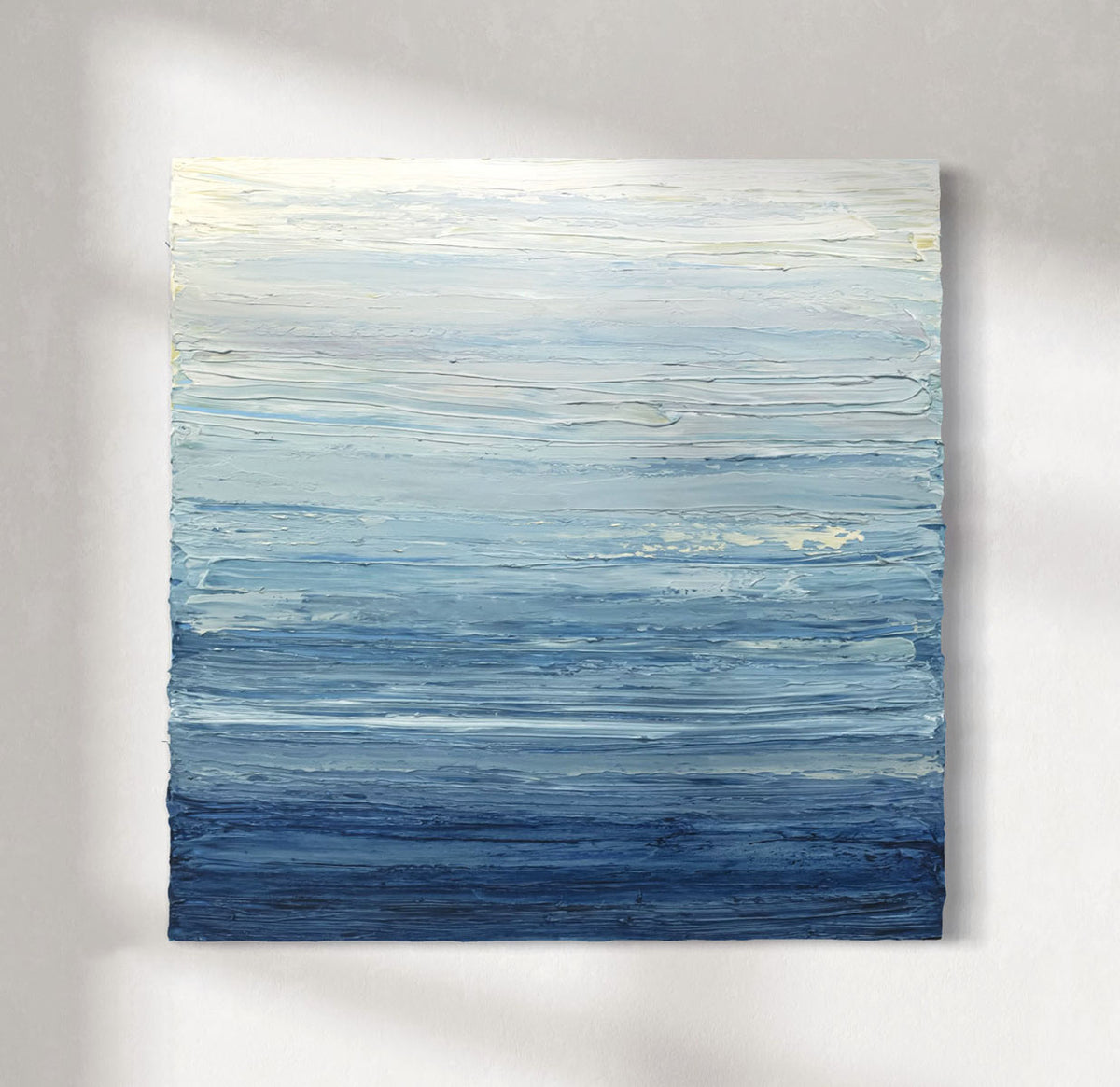 Abstract painting with horizontal brush strokes in blue and white on a gray background hanging on a white wall.