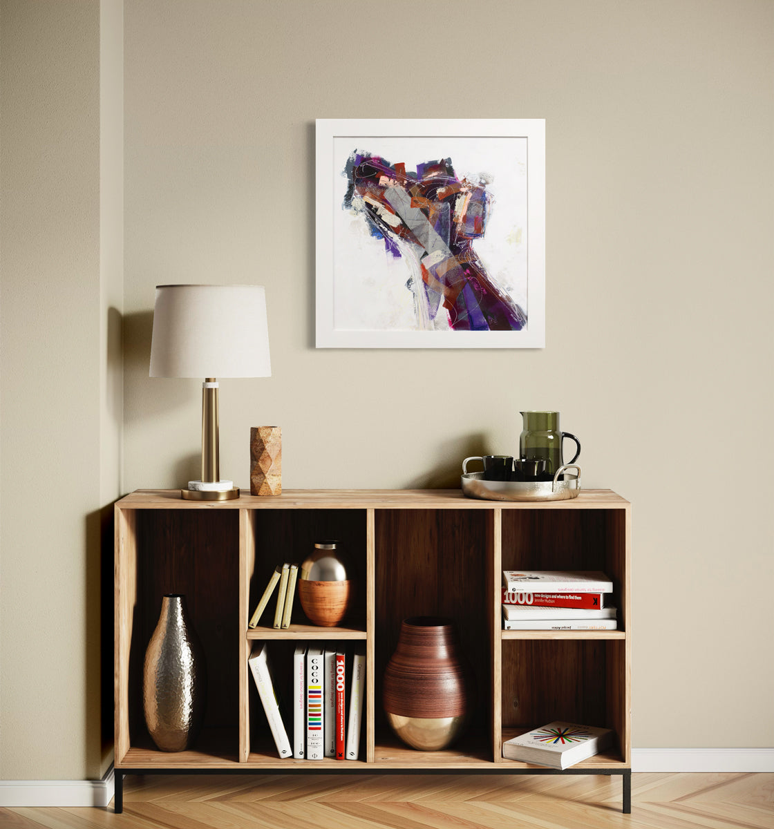 An abstracted painting of a dog in a white frame hangs on a beige wall above a wood console table with modern table decor. 