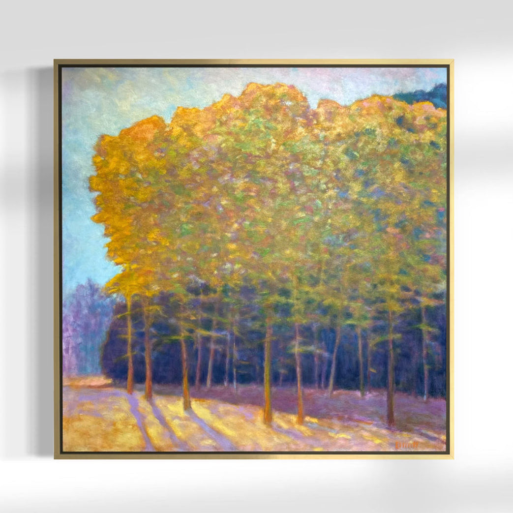 Framed painting of trees with autumn foliage on a white wall