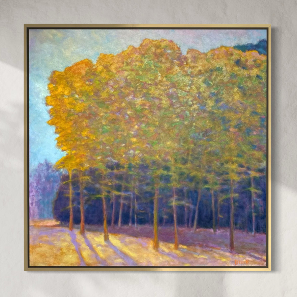 Framed painting of a forest scene with yellow trees on a gray wall.