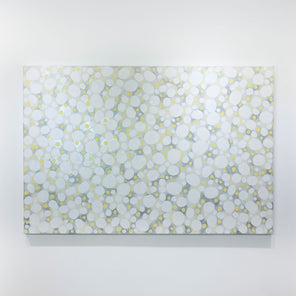 A white, grey, and yellow abstract painting hangs on a white wall. 