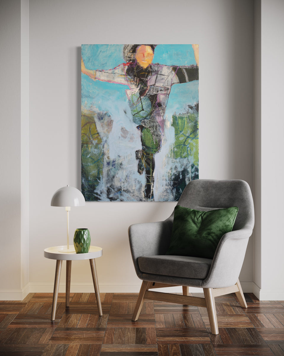 A large abstracted figure painting hangs on a white wall above a grey armchair with green pillow and a minimalist end table with wooden legs and a white table lamp and green vase. 