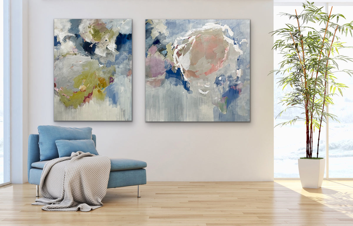 Two abstract paintings on a wall above a blue armchair with a plant in the corner.
