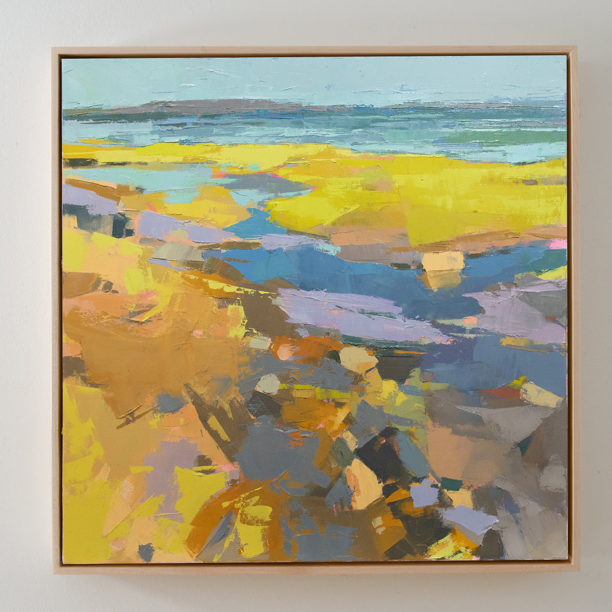 A blue and yellow abstract landscape painting hangs on a white wall. 