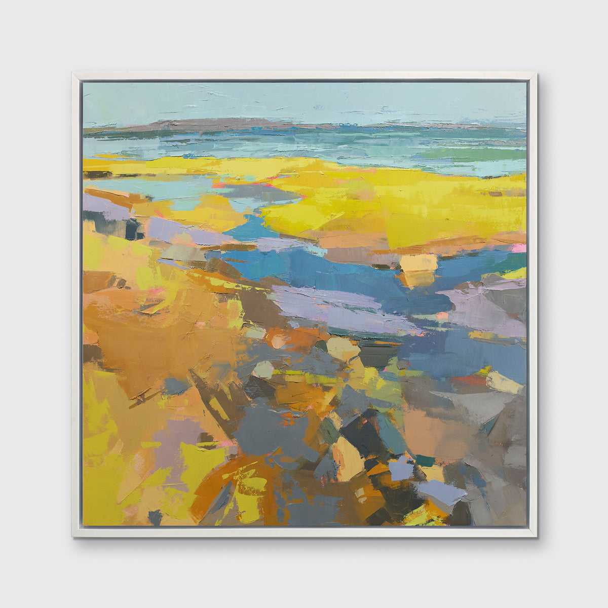 A yellow abstracted landscape print framed in a white frame hangs on a white wall.