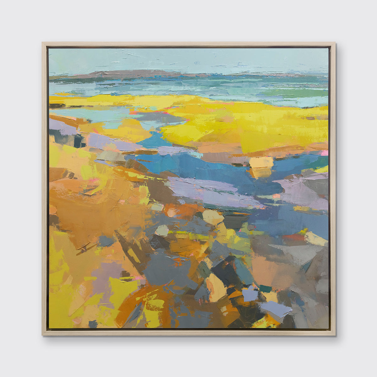 A yellow abstracted landscape print framed in a white oak frame hangs on a white wall.