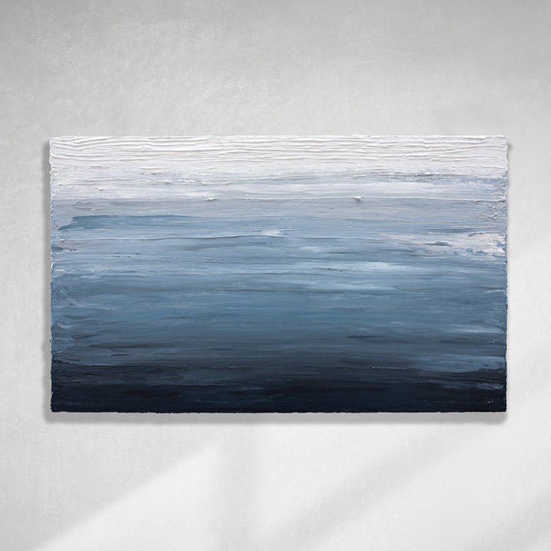 A dark navy blue, light blue, blue, and white thickly textured abstract painting hanging on a white wall in natural light by Teodora Guererra.