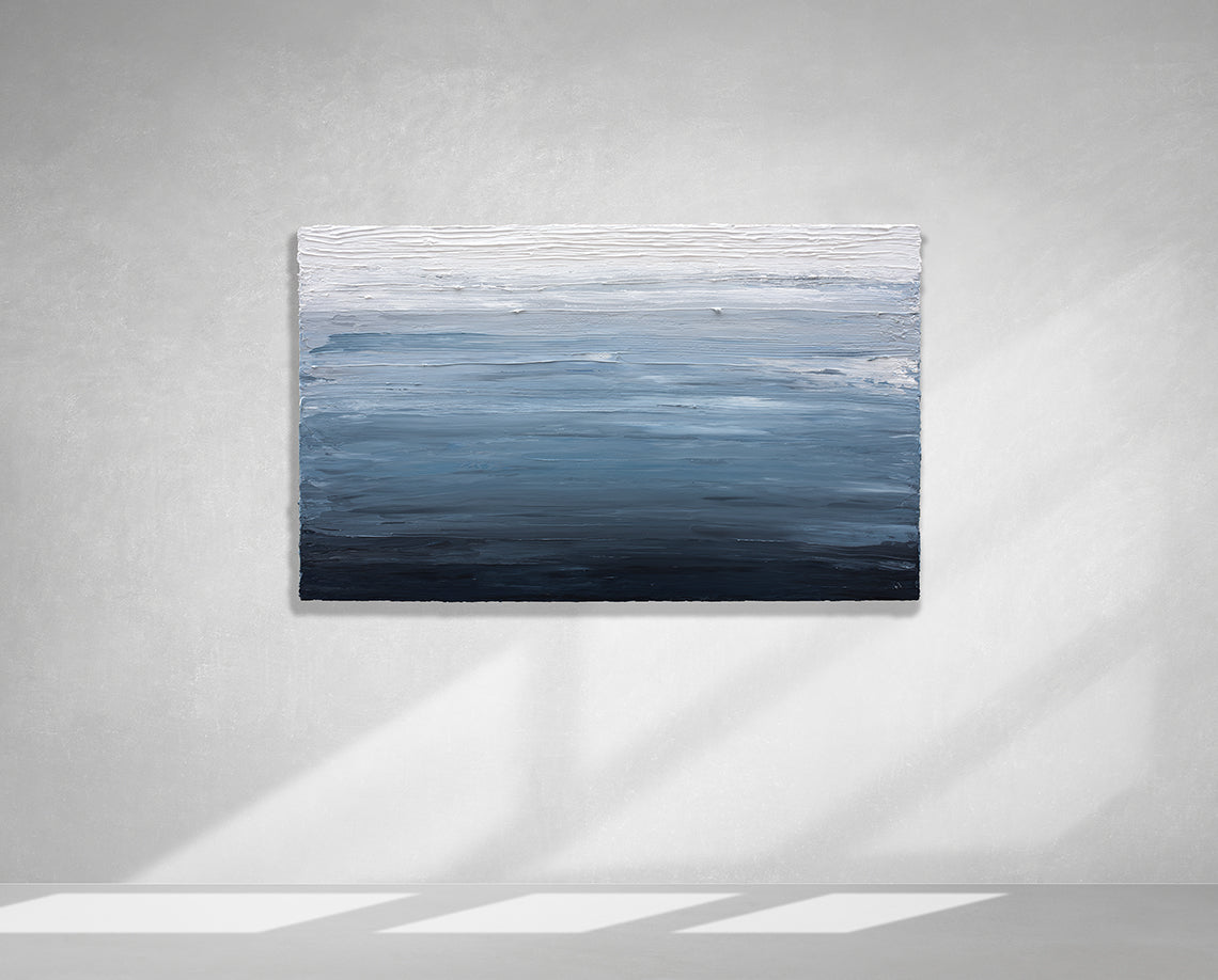 A dark navy blue, light blue, blue, and white thickly textured abstract painting hanging on a white wall in natural light by Teodora Guererra.