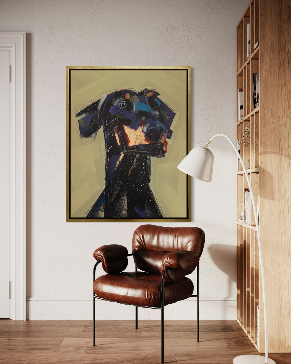 A black, dark purple, copper and chartreuse abstract dog print in a gold floater frame hangs on a white wall next to a wall bookshelf and above a brown leather modern armchair.