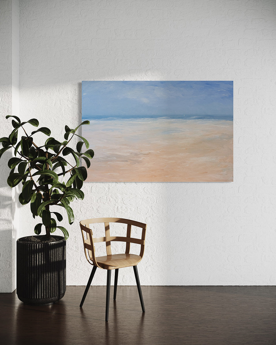 An abstracted coastal seascape painting hangs on white wall above a neutral wood chair with black metal legs and a potted plant to the left..