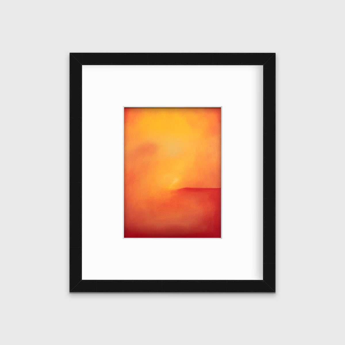 An orange and red abstract print in a black frame with a mat hangs on a white wall.