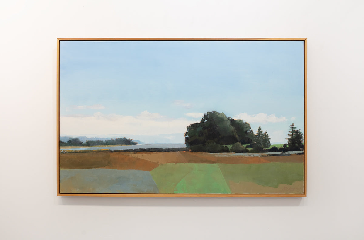 A blue, green, and sienna-toned landscape painting in a light wood frame hangs on a white wall. 
