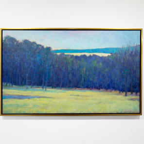 A blue, teal and chartreuse abstract landscape painting by Ken Elliott hangs in a gold faced frame on a white wall.