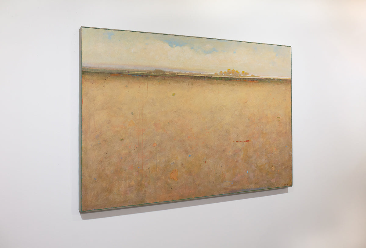 A side view of a beige and blue abstract landscape painting hangs on a white wall.