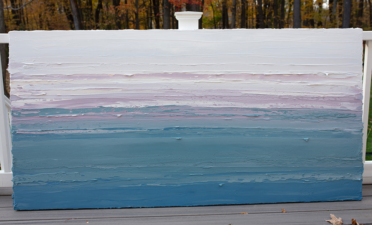 A white, lavender, teal and blue abstract heavily textured painting like sculpture by Teodora Guererra outside in natural light on a deck.