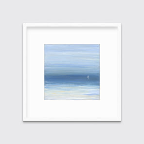 A blue, beige and white abstract seascape print with a small sailboat in a white frame with a mat hangs on a white wall.