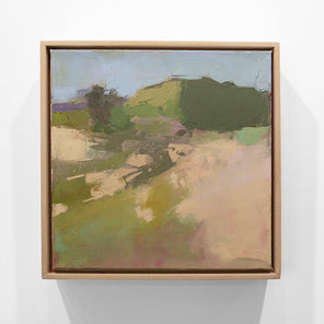 A framed green and warm beige abstracted landscape painting hangs on a white wall.