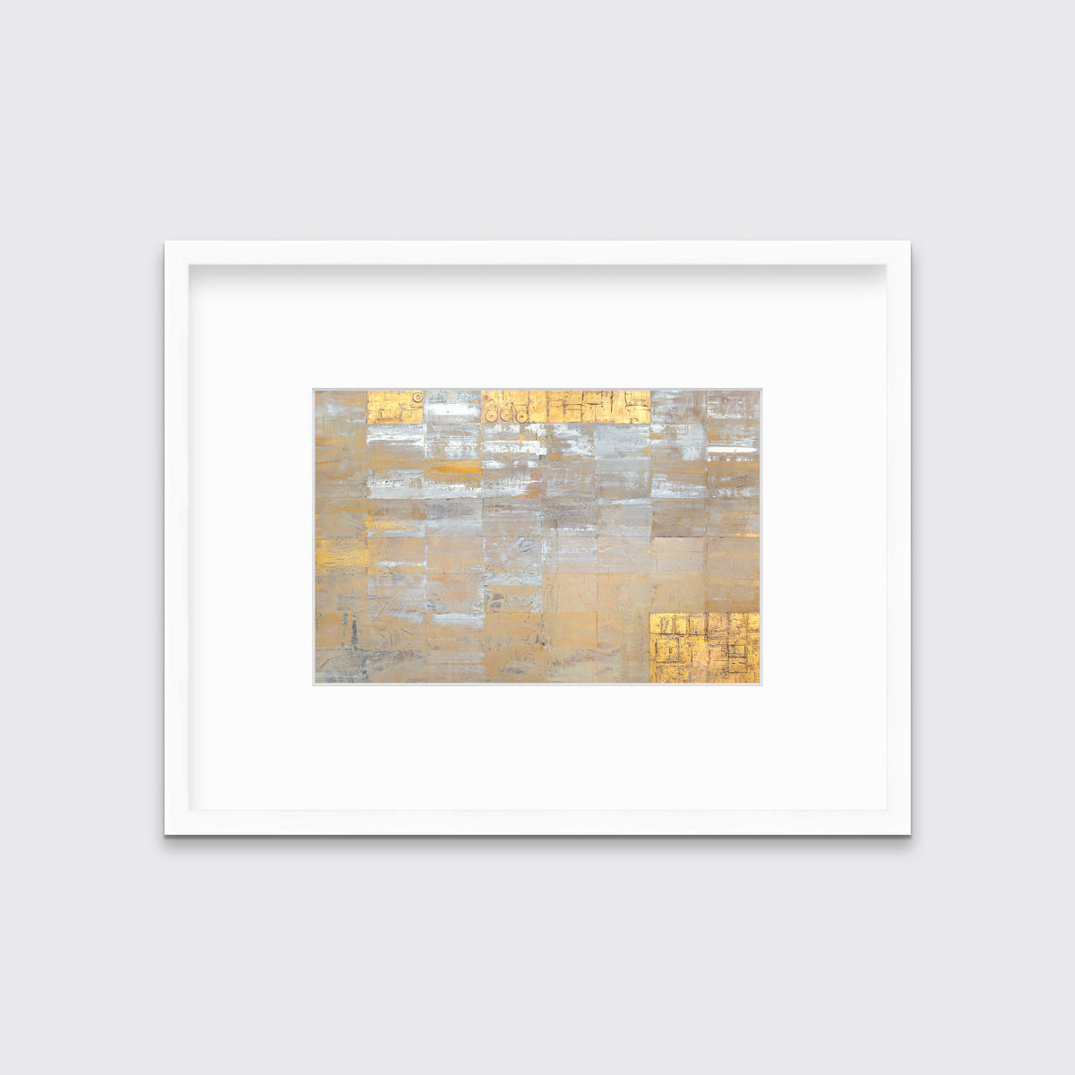 A grey, silver and gold abstract geometric print in a white frame with a mat hangs on a white wall.
