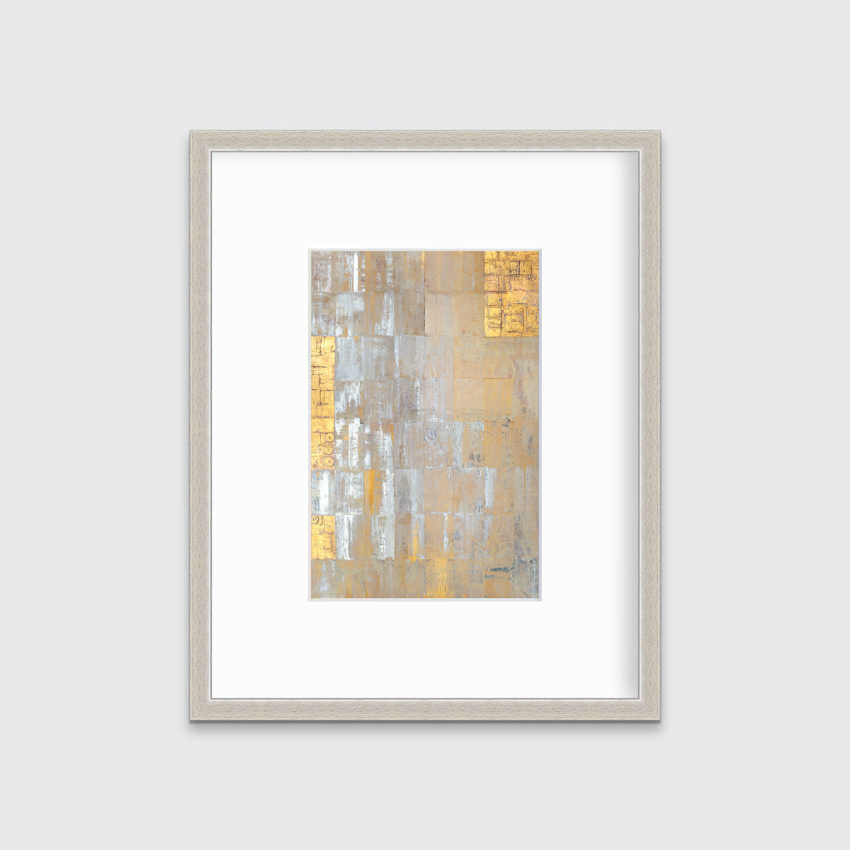 A grey, silver and gold abstract geometric print in a silver frame with a mat hangs on a white wall.