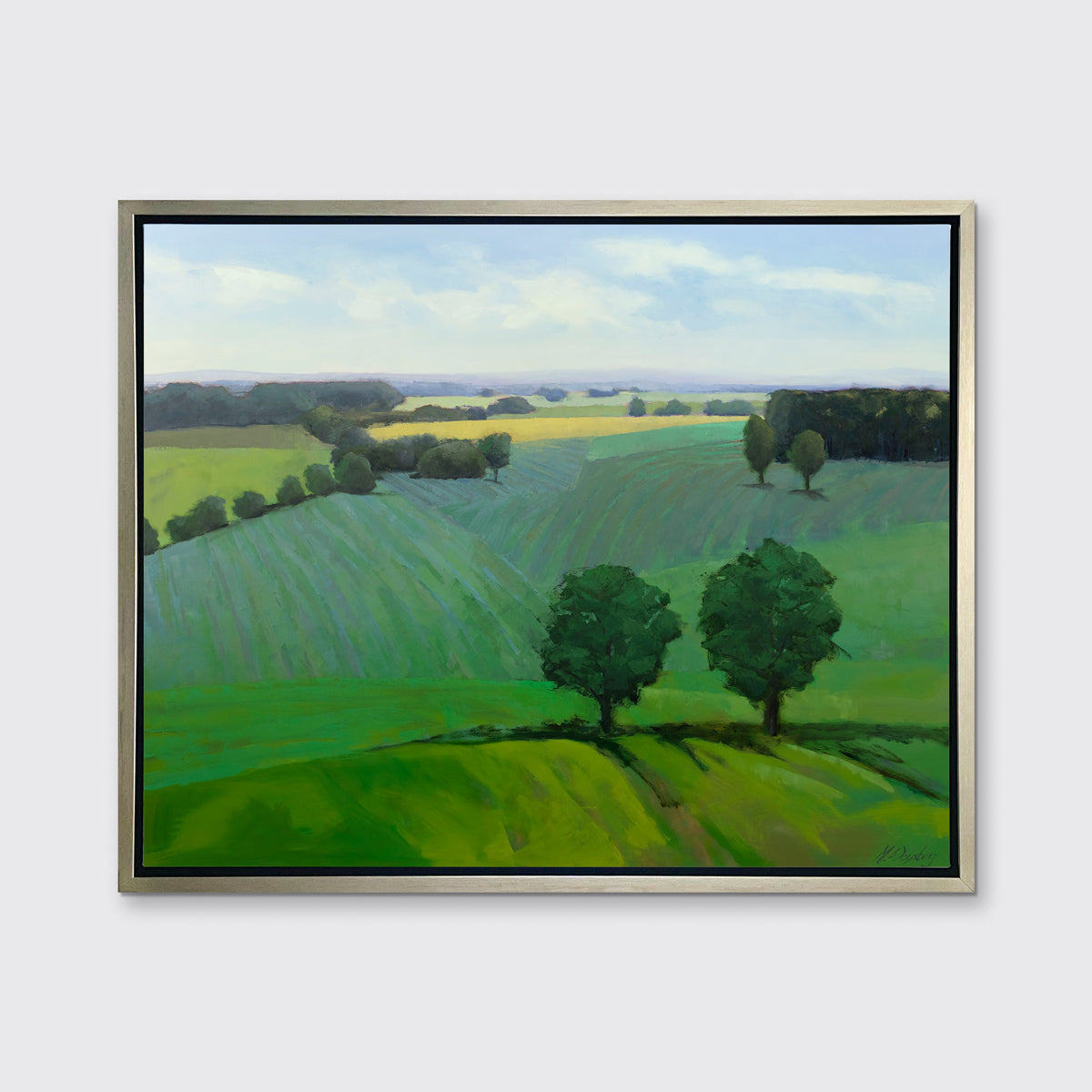 A landscape print in a silver floater frame hangs on a white wall.