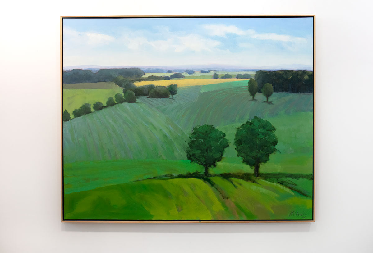 A green landscape painting hangs on a white wall. 