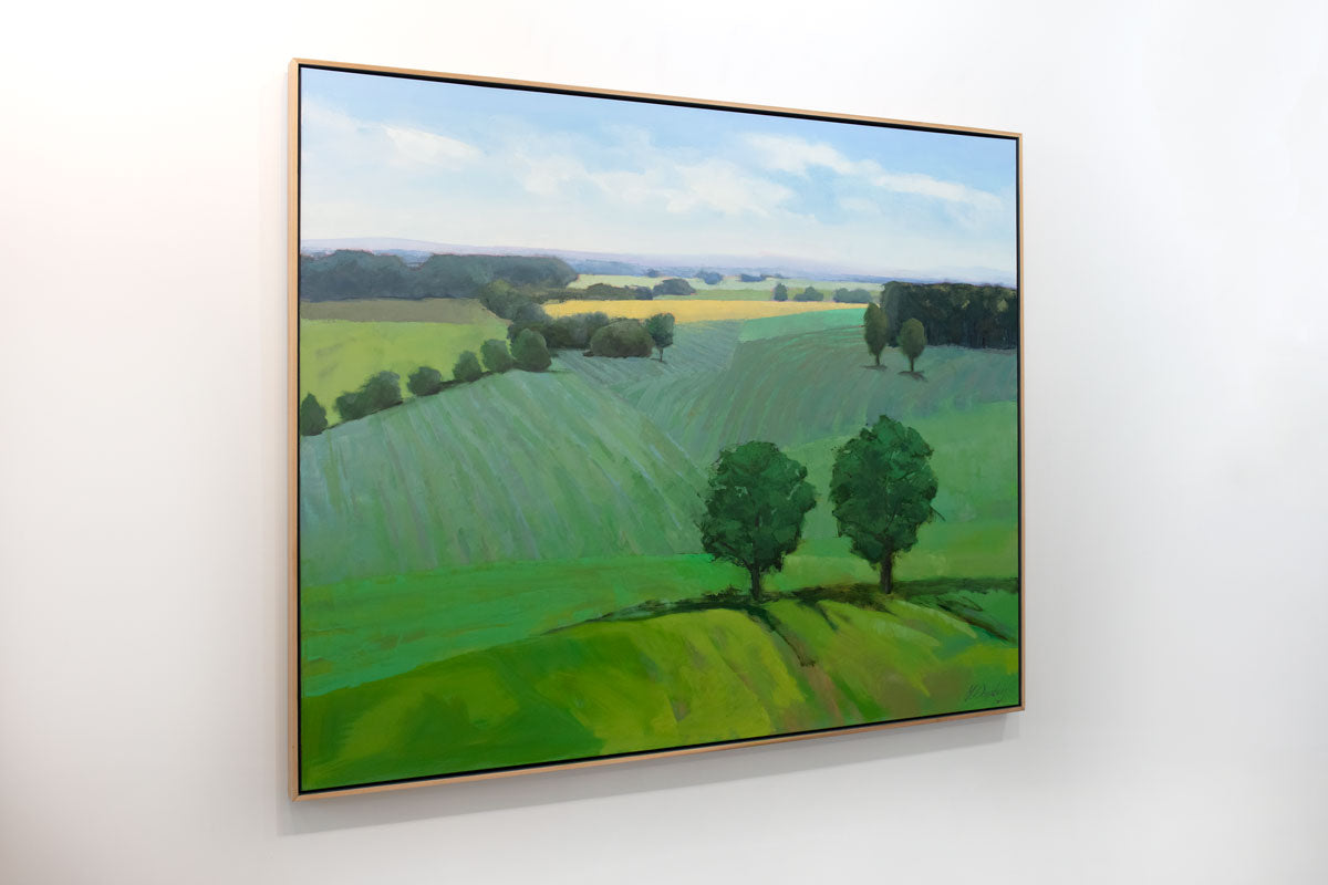 A green landscape painting hangs on a white wall.