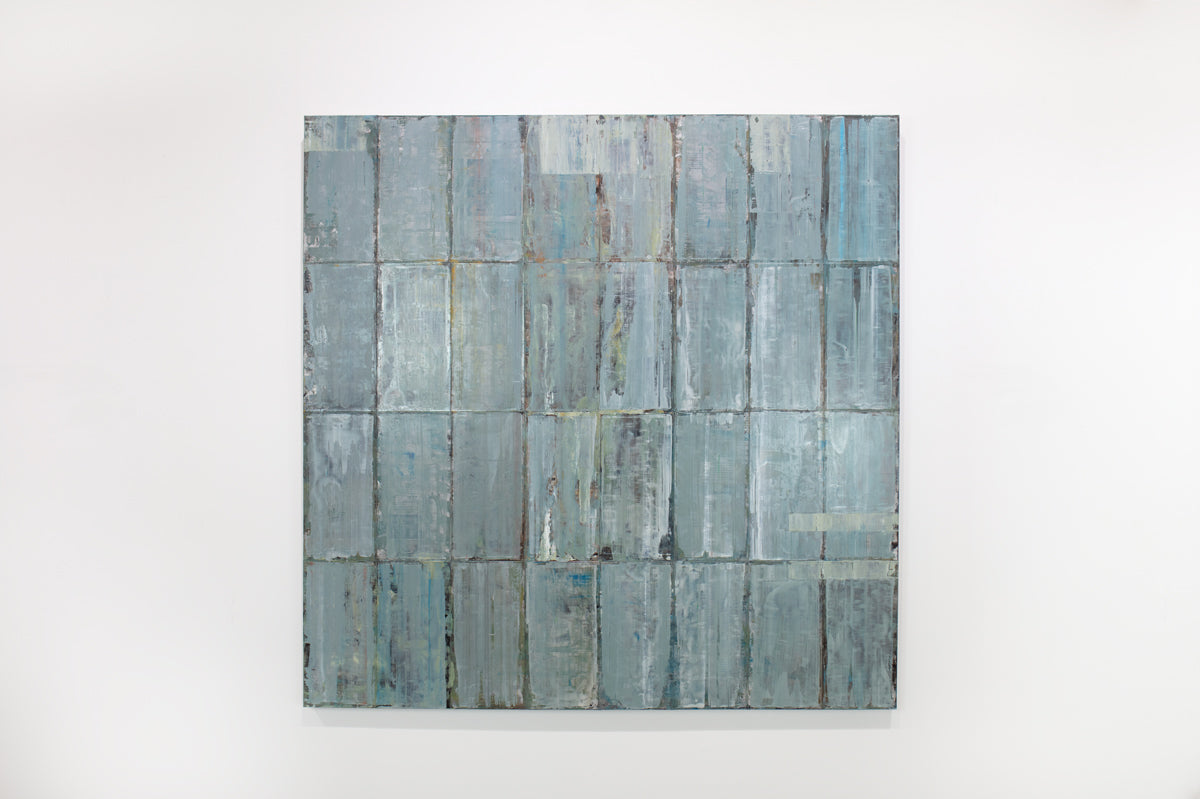 A blue and grey abstract geometric painting hangs on a white wall.